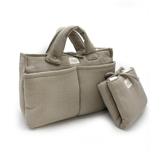 Conjunto de mala de maternidade em musselina bege com molas, ideal para organizar tudo o que o bebé precisa nos passeios, com muda-fraldas portátil a condizer.