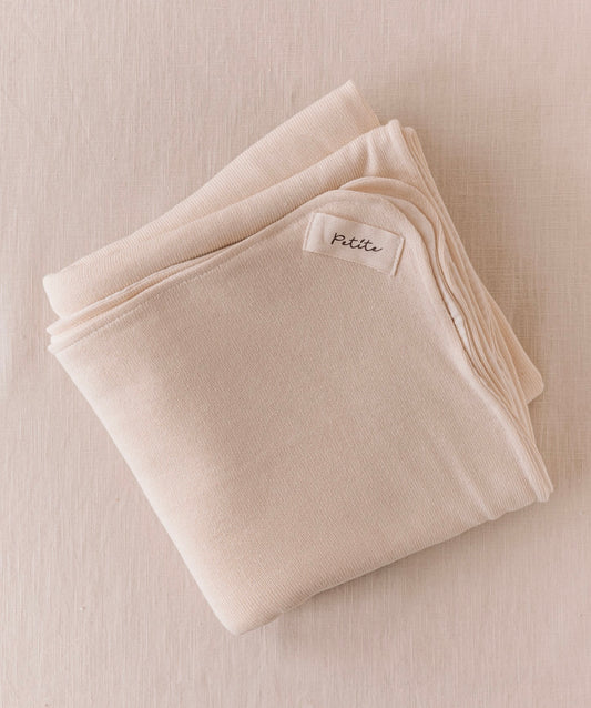 Manta de bebé creme de dupla face, malha macia e musselina de tripla camada, ideal para aconchegar o bebé em casa ou no passeio.