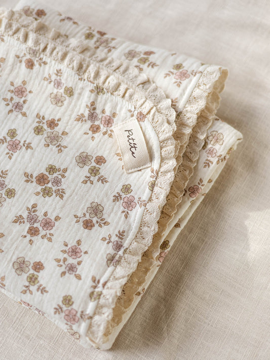 Manta de bebé com motivo floral de dupla face, malha macia e musselina de tripla camada, com rendinha, ideal para aconchegar o bebé em casa ou no passeio.