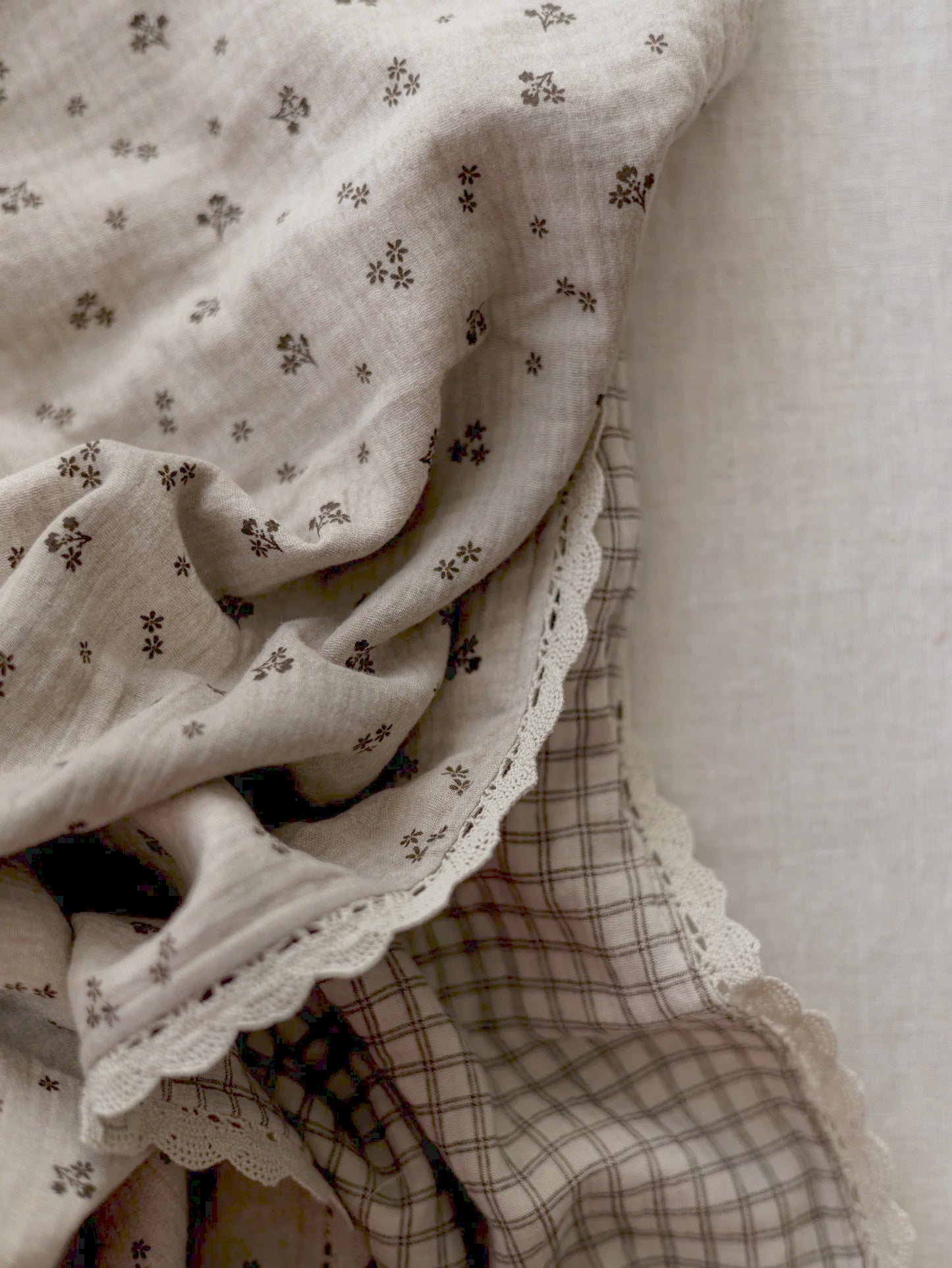 Manta de bebé em tons neutros com motivo floral de dupla face em musselina, com rendinha, ideal para aconchegar o bebé em casa ou no passeio.