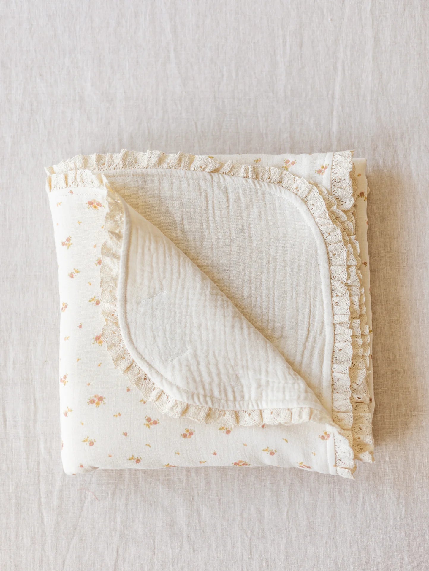 Manta de bebé com motivo floral de dupla face em musselina de tripla camada, com rendinha, ideal para aconchegar o bebé em casa ou no passeio.